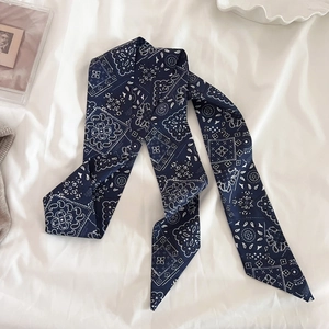 Dettaglio di un foulard in seta blu navy con motivo paisley su tessuto con elementi decorativi