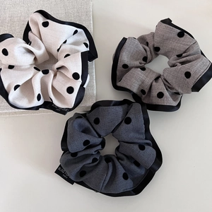 Close-up of three vintage polka dot scrunchies in cream and grey with satin trim detail