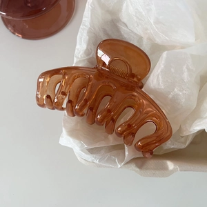 Detailed macro view of the translucent amber jelly hair claw clip on a minimalist background