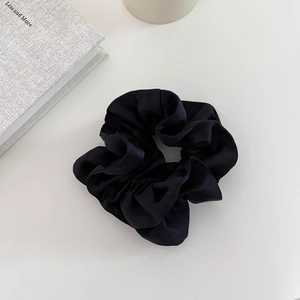 Détail d'un chouchou en satin noir double couche avec une texture de soie douce et plis