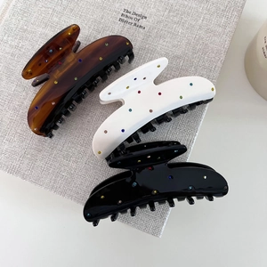 Détail de pinces à cheveux en acétate avec strass colorés posées sur un livre texturé