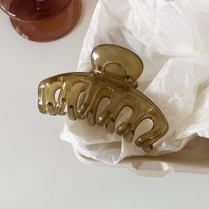Detail of translucent olive green resin hair claw clip with wavy teeth design