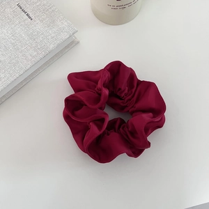 Détail d'un chouchou en satin bordeaux avec texture plissée et brillance soyeuse chic