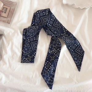 Dettaglio della sciarpa in seta blu scuro con motivo paisley e punte diagonali