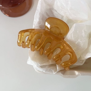 Detail view of a translucent amber resin hair claw clip with a glossy finish and strong grip