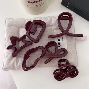 Dettagli di mollette per capelli bordeaux su lino beige con una tazza di ceramica bianca