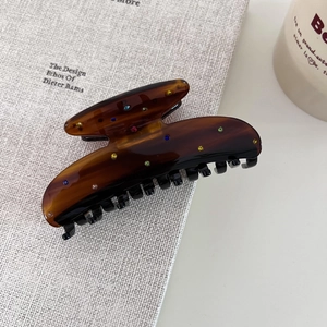 Pince à cheveux en acétate écaille de tortue avec strass colorés sur bureau minimaliste