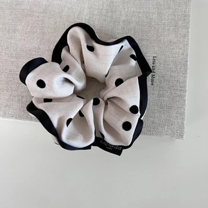Detail showing white polka dot scrunchie fabric and embroidered textile brand label