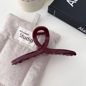 Macro di una molletta per capelli bordeaux con design a torsione lucida su sfondo di lino