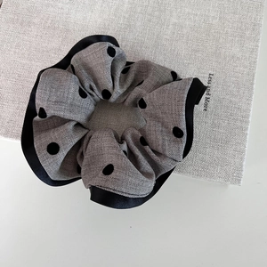 Elegant grey polka dot scrunchie with black satin trim and pleated fabric texture