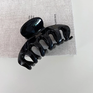 Gros plan détaillé d'une grande pince à cheveux noire brillante gravée Barrette France