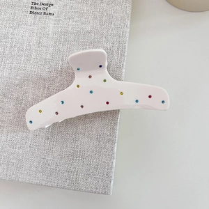 Détail de la pince à cheveux en acétate blanc avec strass colorés et finition brillante