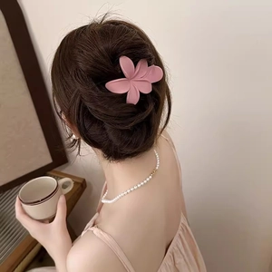 Eleganter mattrosa Blumen-Haarclip für langes Haar in gemütlicher Wohnzimmer-Atmosphäre