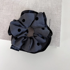 Detailed shot of dark grey polka dot scrunchie with Blind for Love fabric label