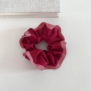 Detail of dark red satin scrunchie with elegant red and white checkered ribbon edge