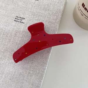 Gros plan d'une pince à cheveux en acétate rouge ornée de strass colorés et étincelants