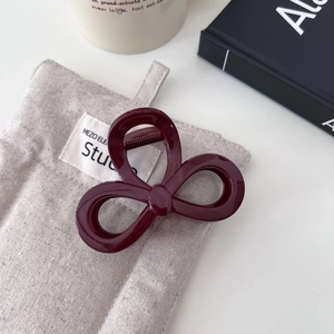 Dettaglio della pinza per capelli a fiocco rosso vino su lino con decoro di libri