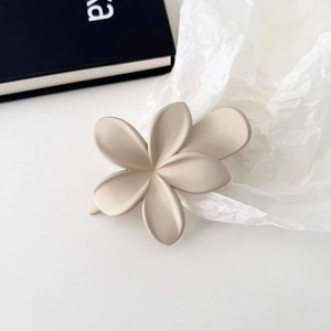 Nahaufnahme der mattbeigen Frangipani-Blütenhaarklammer in elegantem, schlichtem Design