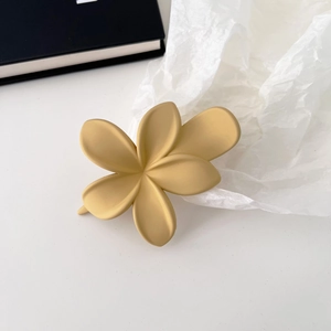 Detailansicht einer mattcremegelben Frangipani-Blüten-Haarklammer auf minimalistischem Hintergrund