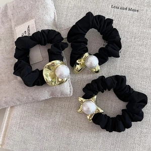 Ensemble de trois chouchous noirs avec charmes dorés et perles d'imitation sur tissu