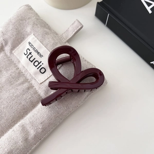 Dettaglio della molletta per capelli bordeaux lucida con design a cuore intrecciato