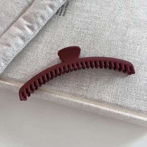 Matte burgundy large crescent hair claw clip for thick hair on a neutral fabric background