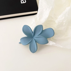 Nahaufnahme einer mattnebelblauen Blumen-Haarklammer auf minimalistischem Hintergrund