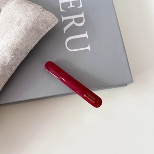 Vue détaillée de la barrette à cheveux en acétate rouge avec texte doré élégant