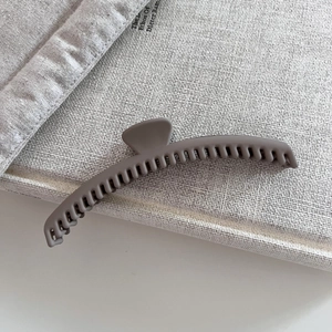 Detailed macro view of matte grey hair claw clip showing dense teeth and frosted texture