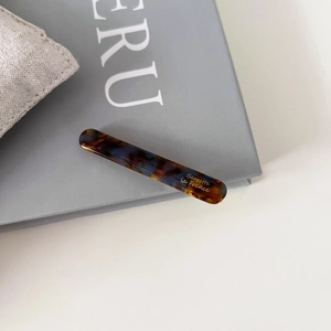 Vue macro d'une barrette baguette en acétate avec motif écaille de tortue et logo doré