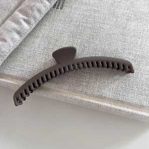 Close-up of matte coffee brown hair claw clip with dense teeth on fabric background