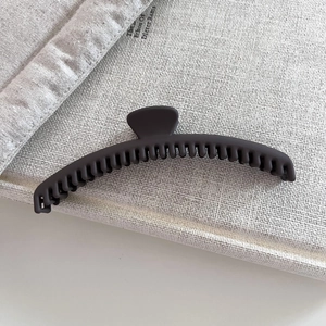 Detailed view of black matte claw clip with long curved teeth on minimalist book