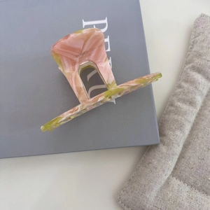 Detail view of pink and yellow marble acetate hair claw with France Handmade gold text