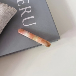 Pince à cheveux baguette en acétate motif marbre avec base en métal doré sur livre