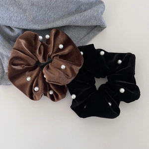 Close-up of coffee and black velvet hair scrunchies decorated with white pearls
