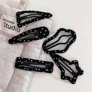 Detailed macro shot of 5-piece black polka dot fabric hair clips in assorted geometric shapes
