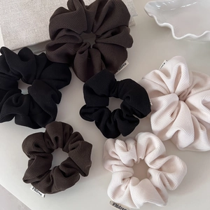 Detailed texture of corduroy scrunchies in autumn earth tones with logo label