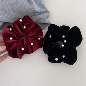 Detail showing plush black and burgundy velvet scrunchies with elegant pearl accents