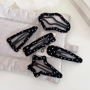 Detailed view of 5-piece black and white polka dot fabric hair clips on linen bag