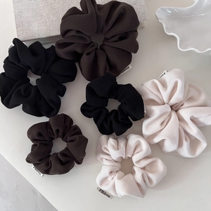 Detail view of corduroy texture scrunchies in autumn tones with brand fabric labels