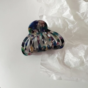 Close-up of a medium acetate shell hair claw with colorful marble texture and hollow design