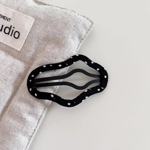 Black and white polka dot cloud fabric BB hair clip on a minimalist textured background