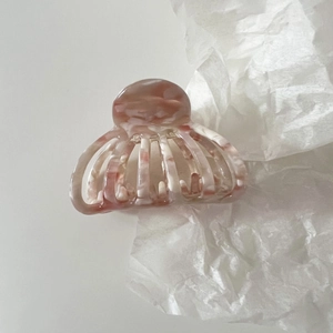 Detail of medium acetate shell hair claw with pink marble texture and hollowed design