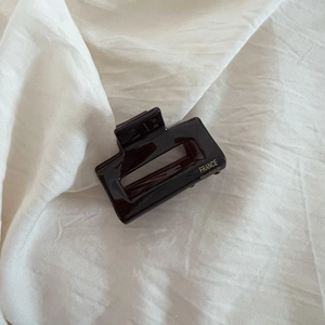 Détail d'une pince à cheveux en acétate marron avec logo France Handmade doré sur tissu