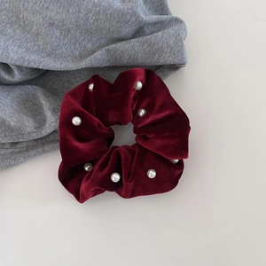 Elegant deep red velvet scrunchie with white pearl accents on minimalist white background