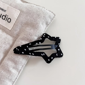 Close-up of a star-shaped black and white polka dot fabric hair clip on a cotton bag