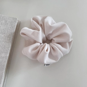 Cream corduroy scrunchie with soft ribbed texture and minimalist brand tag for women
