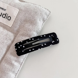 Detailed macro view of black and white polka dot fabric wrapped rectangular metal BB hair clip