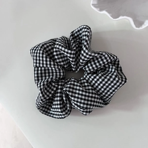 Detailed view of large black and white houndstooth hair scrunchie on white tray