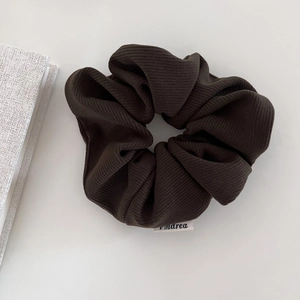 Detail of dark coffee corduroy scrunchie texture with a white woven label on white background